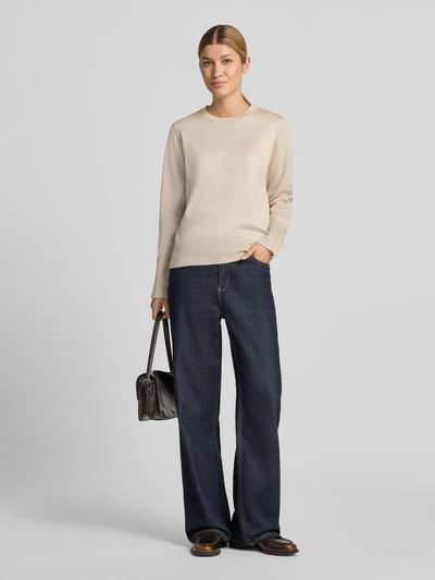 Vrouwenmodel draagt gebreide pullover van viscosemix Model 'KATIE' van FREE/QUENT, recht model, elastische boordjes, knopen aan mouwboord, beige tint, gladde textuur, ruglengte maat S 58 cm, mouwlengte maat S 66 cm, blauwe jeans, zwarte tas, neutrale achtergrond, fullbody vooraanzicht.