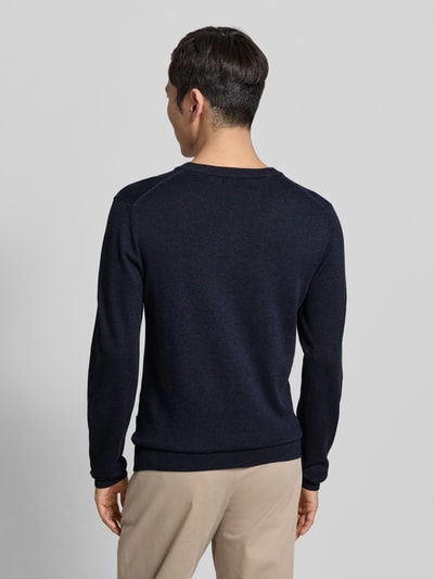 Męski model nosi Strickpullover mit gerippten Abschlüssen Modell 'BELLS' od Casual Friday, granatowy, bawełna z lyocellem, krój slim fit, długi rękaw, okrągły dekolt, długość tyłu w rozm. M: 69 cm, długość rękawa: 68 cm, widok całej sylwetki z tyłu.