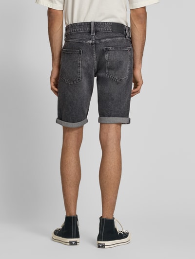 Męski model nosi Regular Fit Jeansshorts aus Baumwoll-Mix od Tommy Jeans, stylizowana na denim, naszywka z logo, krój regular fit, mieszanka bawełny, 5 kieszeni, szlufki na pasek, zapięcie na guzik i ukryty zamek błyskawiczny, widok całej sylwetki z tyłu.