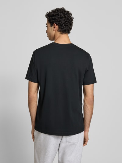 Männermodel trägt T-Shirt mit Label-Stitchings und Rundhalsausschnitt von CHAMPION in Schwarz, Reine Baumwolle, Regular-Fit, Rückenlänge 69 cm, Ganzkörperansicht Rückansicht.