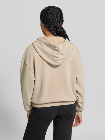 Frauenmodel trägt Oversized Hoodie aus reiner Baumwolle von Lala Berlin in Beige mit Kapuze, gerippten Abschlüssen, Rückenansicht, Ganzkörperansicht Rückansicht.
