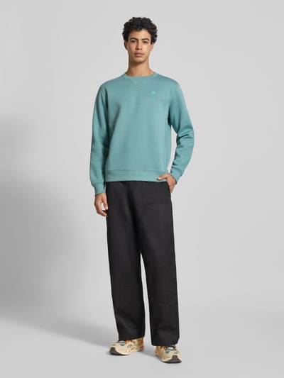 Männermodel trägt Sweatshirt mit Rundhalsausschnitt und Label-Stitching von G-Star Raw in Grün, Baumwoll-Mix, Regular-Fit, Ganzkörperansicht von vorne.