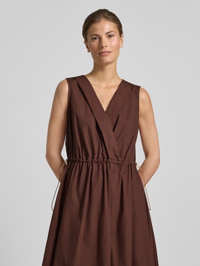 Frauenmodel trägt knielanges Cocktailkleid mit Kordelzug und Kordelstoppern von Rinascimento aus Reine Baumwolle, Taillierter Schnitt, V-Ausschnitt, in Braun mit feiner Textur, Nahaufnahme Oberkörper.