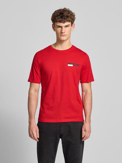 Męski model nosi czerwony T-Shirt mit Label-Print Modell 'CORP' od JACK & JONES, bawełna, prosty krój, widok całej sylwetki z przodu.