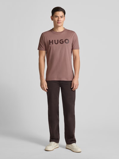 Männermodel trägt Regular Fit T-Shirt aus reiner Baumwolle Modell 'DULIVIO' von HUGO in Unifarben mit Label Print, Ganzkörperansicht von vorne.