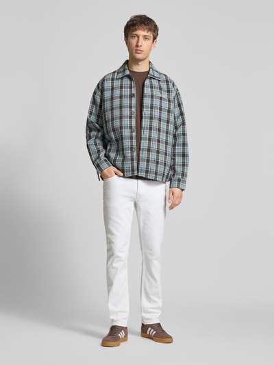 Męski model nosi Slim Fit Jeans mit Eingrifftaschen od Calvin Klein Jeans, materiał z bawełną, kolor biały, szerokość w rozmiarze 32/32: 43 cm, długość nogawki wewnętrznej: 78 cm, krój slim fit, zapięcie na guzik i zamek, widok całej sylwetki z przodu.
