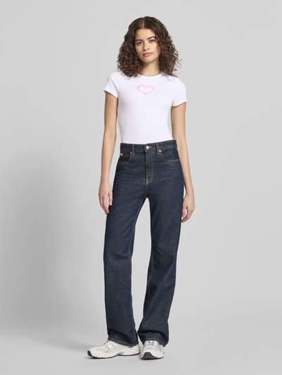 Frauenmodel trägt T-Shirt mit Rundhalsausschnitt Modell 'PREPPY HEART' von Review, weißer Baumwoll-Mix, gerader Schnitt, Ganzkörperansicht von vorne.