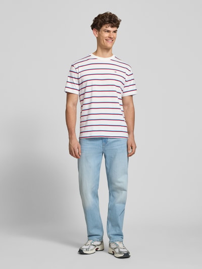 Männermodel trägt Regular Fit T-Shirt aus reiner Baumwolle von Tommy Jeans, Optik:Allover-Muster, gestreift, Ganzkörperansicht von vorne.