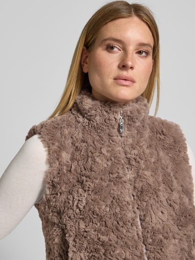 Frauenmodel trägt Regular Fit Weste aus Kunstfell mit Stehkragen von monari, beige, texturierte Oberfläche, Nahaufnahme Oberkörper. Damen Weste, Kunstfell, Reißverschluss, Rückenlänge 47 cm, Schulterbreite 39 cm, Brustweite 45 cm.
