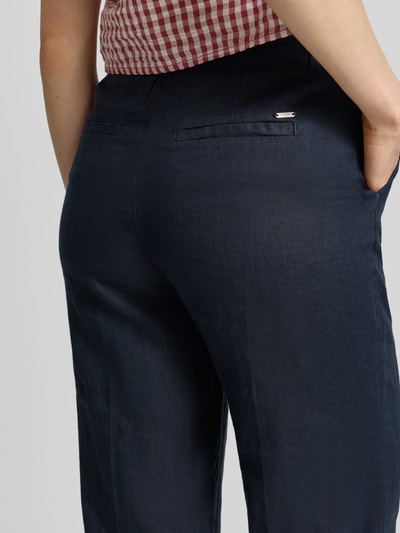 Frauenmodel trägt Leinenhose in verkürzter Passform von Christian Berg Woman, reines Leinen, Eingrifftaschen, Paspeltaschen am Gesäß, Nahaufnahme Rückansicht.