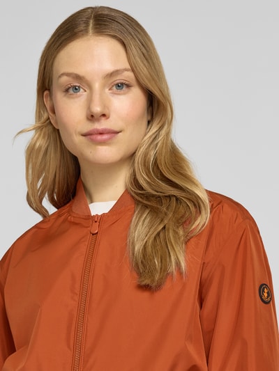 Frauenmodel trägt Jacke mit Zweiwege-Reißverschluss Modell 'OLEN' von SAVE THE DUCK in Rostorange, Material-Mix, Nahaufnahme Oberkörper.