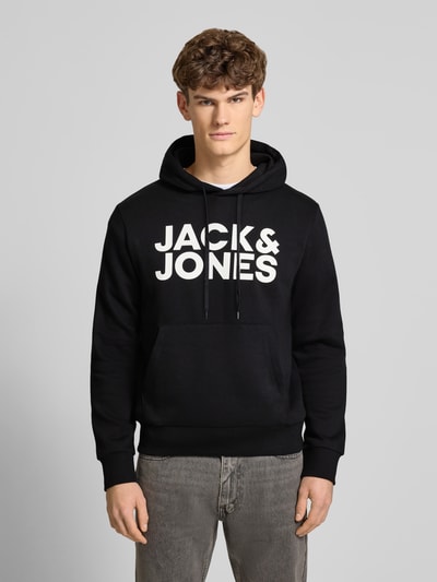Männermodel trägt Hoodie mit Label-Print und Känguru-Tasche von Jack & Jones, schwarz, Baumwoll-Mix, Regular Fit, Ganzkörperansicht von vorne.