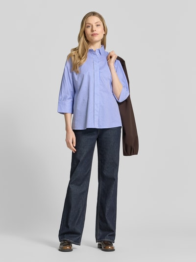 Frauenmodel trägt Regular Fit Hemdbluse mit durchgängiger Knopfleiste von Christian Berg Woman in Hellblau mit feinem Streifenmuster, reine Baumwolle, Halbarm, kombiniert mit dunkler Hose, Ganzkörperansicht von vorne.