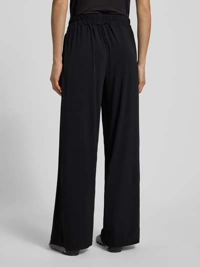 Vrouwenmodel draagt zwarte Stoffhose in verkürzter Passform Modell 'LIMA' van ICHI, los model, elastische tailleband, volledige achteraanzicht.