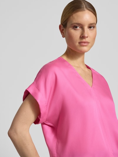 Vrouwenmodel draagt Relaxed Fit Bluse aus reinem Lyocell van Lanius in felroze, korte mouwen, V-hals, gladde textuur, borst-detail, close-up bovenlichaam