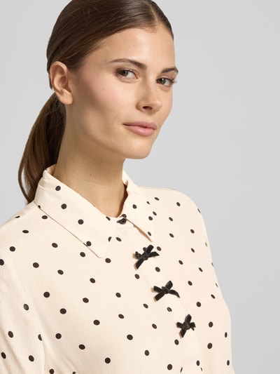 Frauenmodel trägt Regular Fit Hemdbluse aus reiner Viskose Modell 'Lovy' von FREE/QUENT mit Zierschleifen, creme mit schwarzen Punkten, Nahaufnahme Oberkörper.