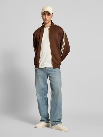 Männermodel trägt Relaxed Fit Sweatjacke mit Kontraststreifen Modell 'RIBER' von Only & Sons in Braun, Optik: Unifarben, Ganzkörperansicht von vorne, Passform: Relaxed-Fit, Verschluss: Reißverschluss, Kragenform: Stehkragen, Applikation: Kontraststreifen, Ärmelabschluss und Rumpfabschluss: gerippt, Materialverarbeitung: Sweat, mit seitlichen Eingrifftaschen.
