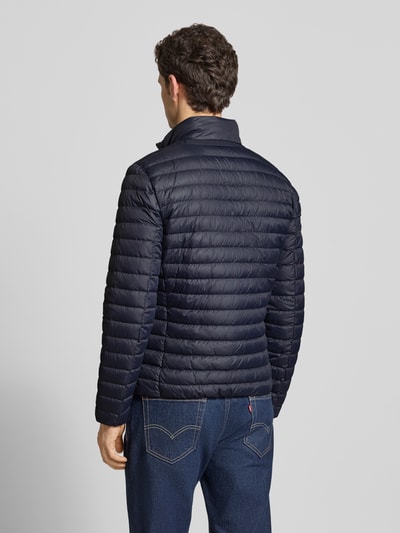 Mannelijk model draagt donkerblauw gewatteerd jack met opstaande kraag en tweewegritssluiting van Geox, regular fit, ruglengte 64 cm, schouderbreedte 46 cm, borstwijdte 49 cm, mouwlengte 65 cm, ritszakken, ganzkörperansicht achteraan.