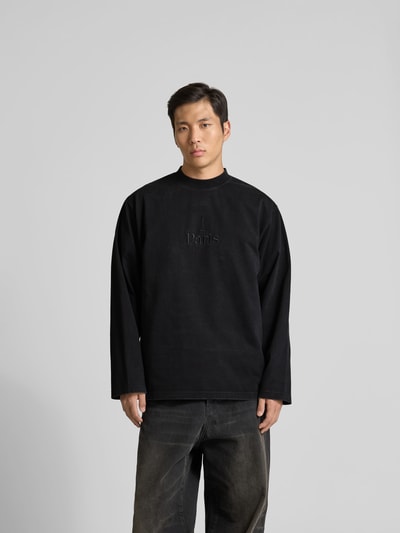 Männermodel trägt Regular Fit Sweatshirt aus Baumwolle von VETEMENTS in Schwarz mit Stehkragen und Statement-Stitching, ganzkörperansicht von vorne. Reine Baumwolle, Regular-Fit, Langärmeliges Design, Rückenlänge 80 cm bei Größe M.
