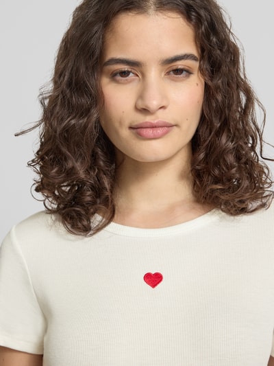 Frauenmodel trägt Slim Fit T-Shirt mit Herz-Stickerei Modell 'ELVA JUNE' von Only, unifarben, Rippstruktur, Nahaufnahme Oberkörper.