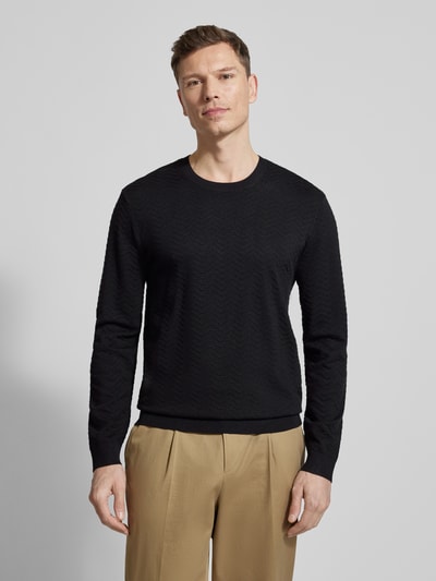 Männermodel trägt schwarzen Strickpullover aus Viskose-Mix von ARMANI EXCHANGE, Rundhalsausschnitt, elastische Abschlüsse, Ganzkörperansicht von vorne.