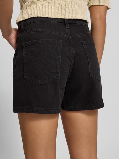 Frauenmodel trägt Jeansshorts im 5-Pocket-Design Modell 'ZOEY' von Mango aus Reine Baumwolle, Straight, schwarze Waschung, Ganzkörperansicht Rückansicht.