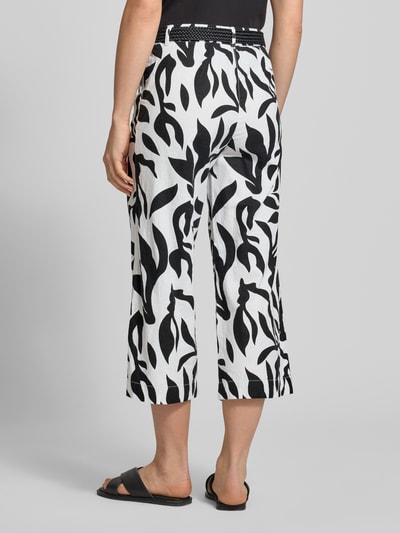 Frauenmodel trägt Culotte aus Leinen-Baumwoll-Mix mit Gürtel von Christian Berg Woman, Allover-Look in Schwarz-Weiß, Ganzkörperansicht Rückansicht.