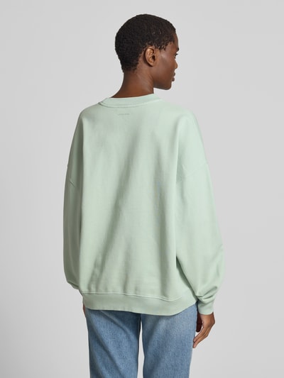 Frauenmodel trägt Oversized Sweatshirt mit Logo-Stitching von Anine Bing aus Reiner Baumwolle in Mintgrün, Oversized-Fit, elastische Abschlüsse, Rundhalsausschnitt, Rückenlänge bei Größe S 63 cm, Ganzkörperansicht Rückansicht.