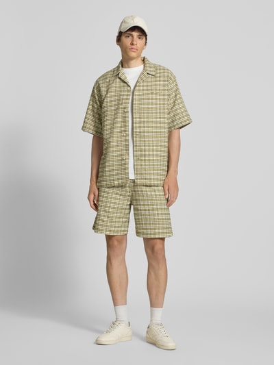 Männermodel trägt Shorts mit Strukturmuster Modell 'Kander' von Carhartt Work In Progress, grün-beige, Reine Baumwolle, Ganzkörperansicht von vorne.