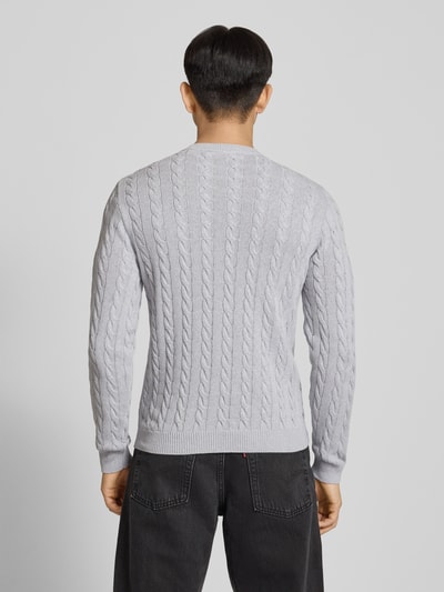 Mężczyzna nosi Strickpullover mit Zopfmuster und Logo-Stitching od REVIEW, bawełniany, krój modern fit, jasnoszary, fason z okrągłym dekoltem, widoczne sploty, prążkowane ściągacze, całkowity widok z tyłu.