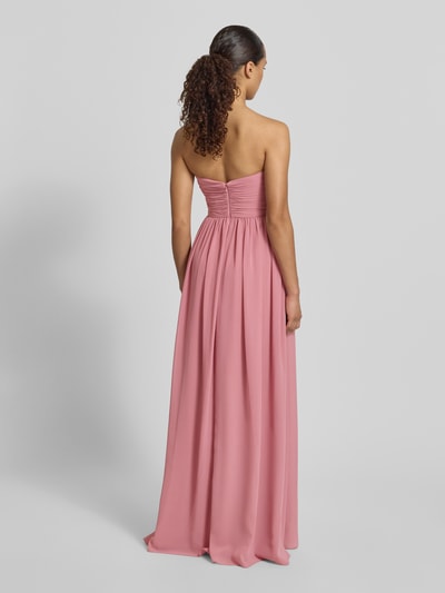 Frauenmodel trägt Maxikleid im Off-Shoulder-Look von Mascara aus rosafarbenem Chiffon mit tailliertem Schnitt, Rückansicht Ganzkörperansicht.