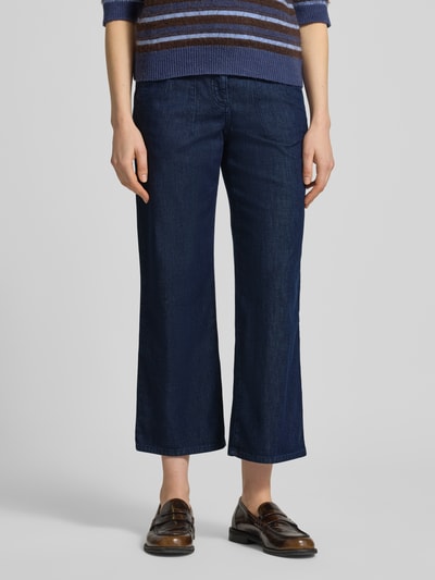Frauenmodel trägt Wide Leg Jeans in verkürzter Passform Modell 'Maine' von Brax, dunkelblauer Baumwoll-Mix, Nahaufnahme Oberkörper bis Knöchel.