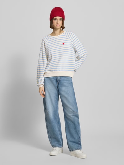 Frauenmodel trägt Oversized Sweatshirt aus Baumwoll-Mix Modell 'GRETA' von Pieces in Two-Tone, gestreift, unifarben mit Label-Stitching-Applikation, gerippt an Ärmel- und Rumpfabschluss, Rundhals, Webware-Optik, Ganzkörperansicht von vorne.