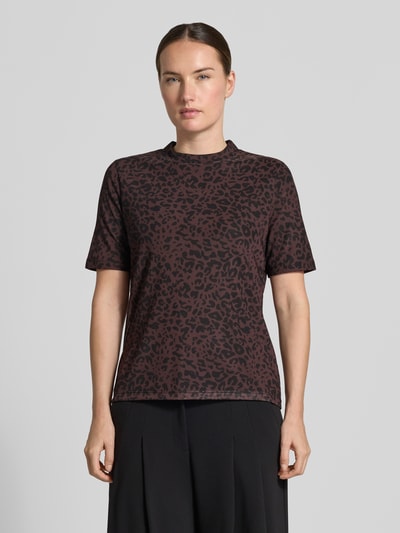 Frauenmodel trägt T-Shirt mit Leo-Print von MORE & MORE, braun-schwarzer Muster-Mix, gerader Schnitt, Stehkragen, Ganzkörperansicht von vorne.