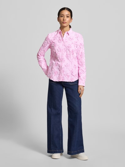 Kobiece modelka nosi HBK Zümdholzstreifen Streifen Bluse mit Blumen Applikationen von Christian Berg Woman, różowe i białe paski, luźny krój, kwiatowe aplikacje, kołnierz koszulowy, materiał z dodatkiem bawełny, całkowita długość tyłu 62 cm, długość rękawa 60 cm, widok całej sylwetki z przodu.