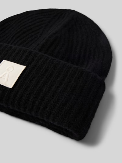 Produktfoto, schwarze Mütze aus reiner Wolle Modell 'ICONIC Å WOOL' von ARMEDANGELS, gerippte Textur, rechteckiges Label, Damen Mütze