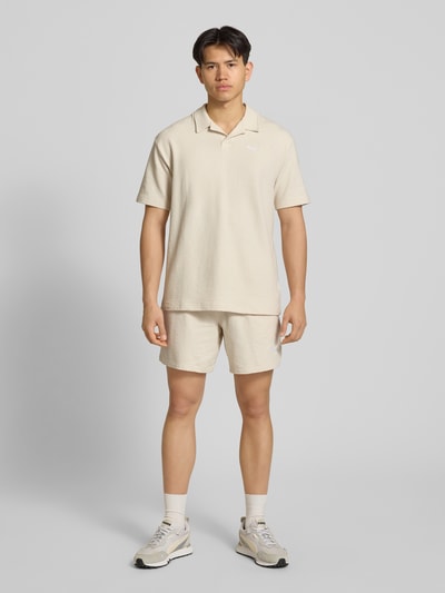 Männermodel trägt Shorts mit Logo-Stitching von PUMA PERFORMANCE aus reiner Baumwolle und Strukturmuster, in Beige, Ganzkörperansicht von vorne.