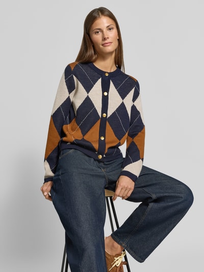 Frauenmodel trägt Regular Fit Strickjacke aus reiner Wolle von GANT in Blau, Braun und Creme mit Rauten, Nahaufnahme Oberkörper. Damen Strickjacke von GANT.