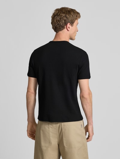 Männermodel trägt T-Shirt mit kurzer Knopfleiste von REVIEW in Schwarz, Feinripp, Baumwoll-Mix mit Stretch-Anteil, Körpernaher-Schnitt, Rückenlänge 64 cm, Ganzkörperansicht Rückansicht.
