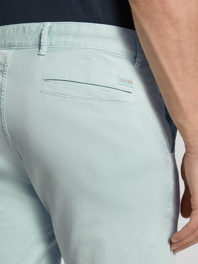 Männermodel trägt Slim Fit Chinoshorts aus Baumwoll-mix von BOSS Orange, hellblau, mit Label-Applikation, Nahaufnahme Rückansicht.