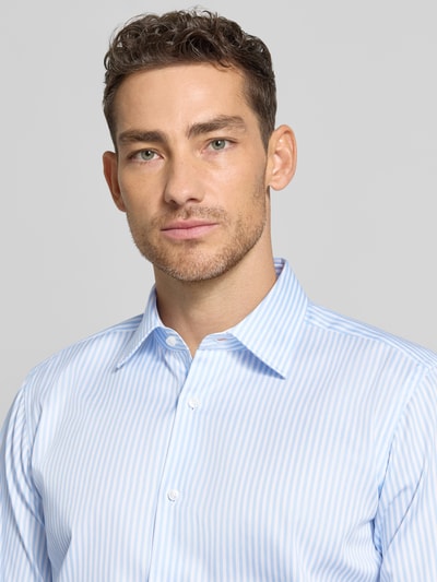 Męski model nosi Regular Fit Businesshemd aus reiner Baumwolle Modell 'JOE' od BOSS, wzór w paski, materiał bawełna, krój regular fit, koszula biznesowa, jasnoniebiesko-białe kolory, długi rękaw, kołnierzyk kent, guziki, tekstura gładka, optyka allover, zbliżenie na górną część ciała z przodu.