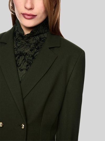 Frauenmodel trägt Slim Fit Blazer mit Reverskragen und Pattentaschen von Marc Cain, olivgrün, feiner Material-Mix, Nahaufnahme Oberkörper. Damen Blazer von Marc Cain mit Viskose-Anteil, Zweireiher, Rückenlänge 56 cm, Brustweite 47 cm, Ärmellänge 60 cm.