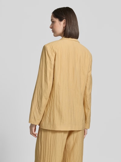 Frauenmodel trägt Straight Fit Blazer aus Viskose-Mix mit Strukturmuster von Jake*s Collection in Beige mit Reverskragen, Pattentaschen und Knopfverschluss, Leinen-Viskose-Anteil, Ganzkörperansicht Rückansicht.