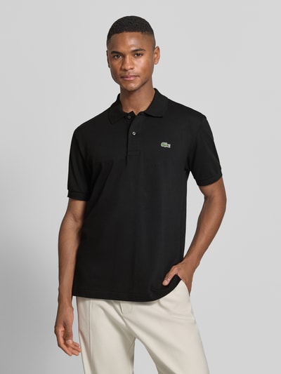 Männermodel trägt schwarzes Regular Fit Poloshirt aus Baumwoll-Mix von Lacoste, Optik: Unifarben, Logo-Detail, Piqué, Ganzkörperansicht von vorne.