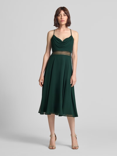 Modelka nosi knielanges Cocktailkleid mit Wasserfall-Ausschnitt von Vera Mont z szyfonu, taliowany krój, długość do kolan, tasiemka w talii z szydełkowej koronki, długość tyłu w rozmiarze 36: 88 cm, szerokość klatki piersiowej w rozmiarze 36: 33 cm, widok całej sylwetki z przodu