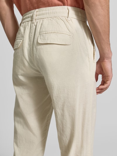Mężczyzna nosi Hose aus Leinen-Baumwoll-Mix mit elastischem Bund von Lindbergh, krój regular fit, jasny beż, faktura lniano-bawełniana, szerokość w rozmiarze M 40 cm, długość nogawki od wewnątrz 79 cm, widok tyłu z bliska