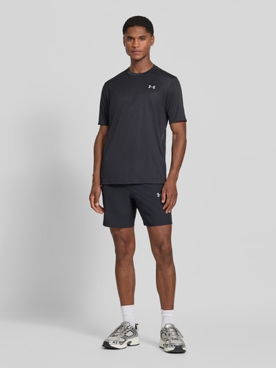 Männermodel trägt Regular Fit Sport-T-Shirt mit Label-Print von Under Armour in Schwarz, glatte Textur, Ganzkörperansicht von vorne. Herren Sport-T-Shirt von Under Armour