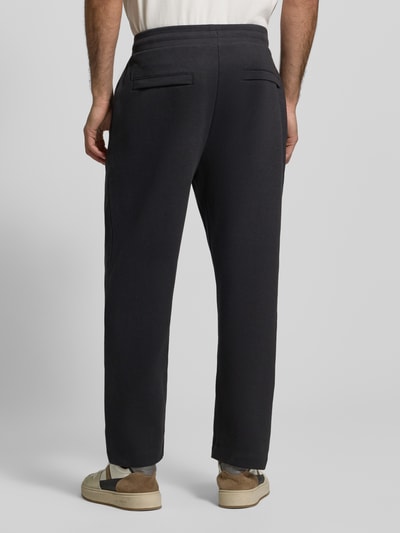 Männermodel trägt Relaxed Fit Sweatpants aus bawełny-mix Modell 'SE_TWIST' von BOSS Orange, efekt: jednolity kolor, melanż, zakładka w pasie, naszywka z logo, elastyczny ściągacz, tunel, kieszenie zapinane na zamek błyskawiczny, wpuszczane kieszenie, wykończenie materiału: dzianina dresowa, widok całej sylwetki z tyłu