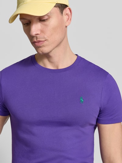 Männermodel trägt Regular Fit T-Shirt aus reiner Baumwolle von Polo Ralph Lauren in Unifarben Lila mit Logo-Stitching, Nahaufnahme Oberkörper