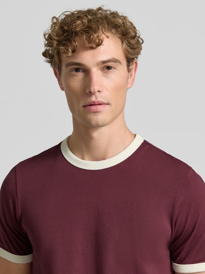 Männermodel trägt Regular Fit T-Shirt aus reiner Baumwolle von MCNEAL in Bordeaux mit kontrastivem Rundhalsausschnitt, Nahaufnahme Oberkörper.